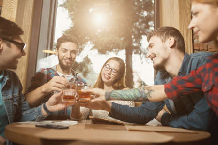 Groups of friends celebrating birthday sitting in cafe, clink glassesの写真素材
