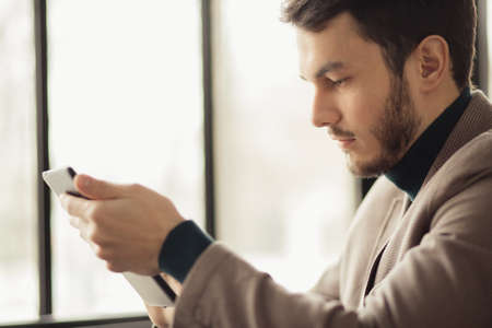Profile view of successful businessman using digital tablet in a cafeの写真素材