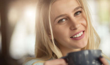 Woman drinking cup of tea in a cafe - closeup