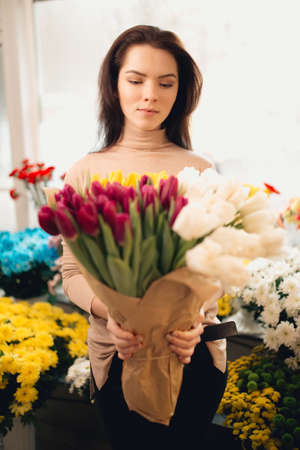 Portrait of pretty women in flowers shop holding bouquet of tulipsの写真素材