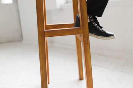 Laconic style - woman in gumshoes sitting on a wooden stool