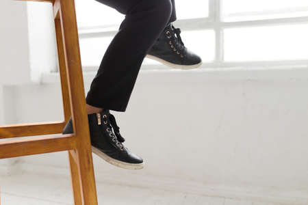 Laconic style - woman in gumshoes sitting on a wooden stoolの写真素材