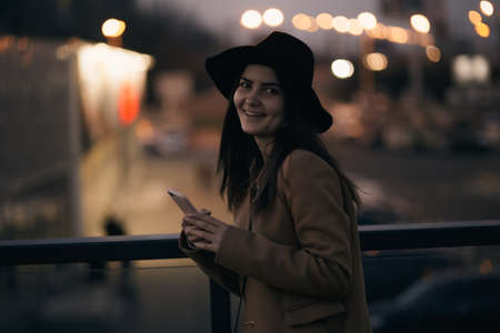 Woman in hat with mobile phone at nightの写真素材