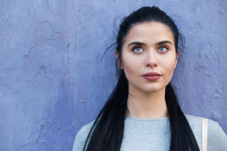 Closeup portrait of woman at violet wall, she looking upの写真素材