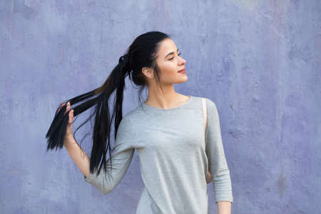 Stylish pretty woman portrait against a violet wall background, she smileの写真素材