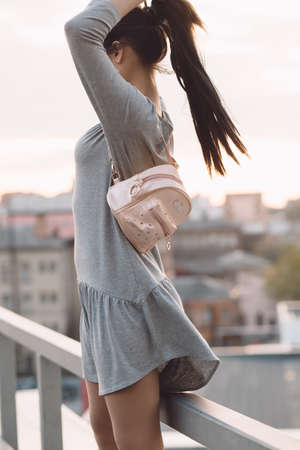 Stylish young woman standing on roof and relaxation, evening city backgroundの写真素材