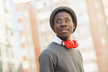 Portrait of african american man with hat and headphones in city street