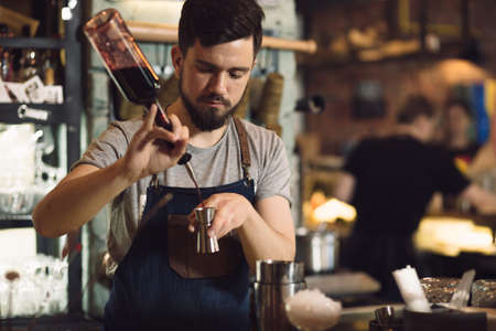 Young male bartender preparing an alcohol cocktail at a bar counterの写真素材