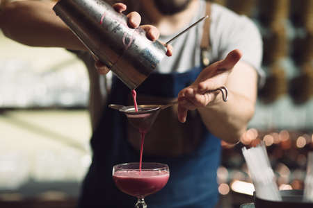 Young male bartender preparing an alcohol cocktail at a bar counter, he percolating juiceの写真素材
