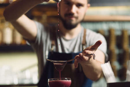 Young male bartender preparing an alcohol cocktail at a bar counter, he percolating juiceの写真素材