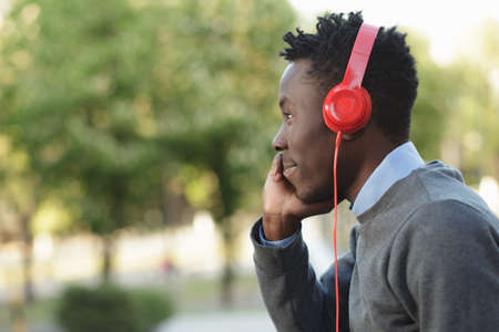 African american man listening to music with his headphones in park at summer dayの写真素材