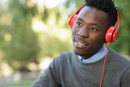 African american man listening to music with his headphones in park at summer day