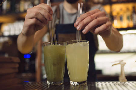 Young male bartender preparing an alcohol cocktail at a bar counterの写真素材