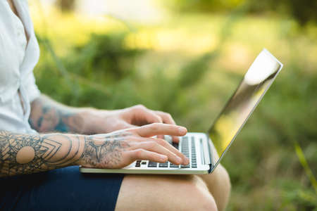 Man freelancer working with laptop in a nature - cropped shotの写真素材