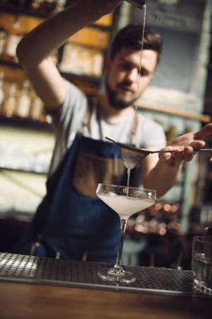 Young male bartender preparing an alcohol cocktail at a bar counter, he percolating juiceの写真素材