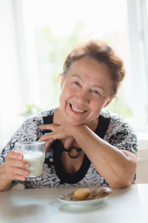 Happy elderly woman eating lunch and drinking milkの写真素材