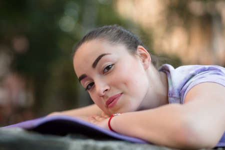 Woman on a sportive mat lying relaxing outdoor. Girl rest in fresh air. Closeup portrait.の写真素材