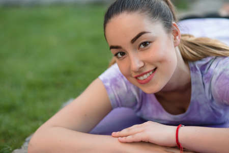 Woman on a sportive mat lying relaxing outdoor. Girl rest in fresh air. Closeup portrait.の写真素材