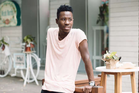 African american man portrait. He sitting near white stylish cafe.の写真素材