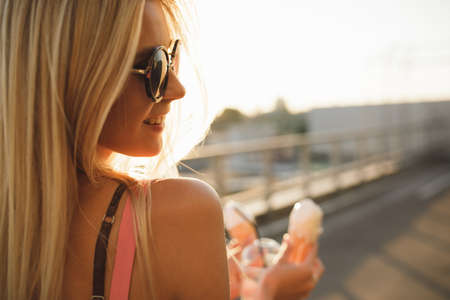 Joyful woman in city sunset eating ice cream, she enjoy summer holidayの写真素材