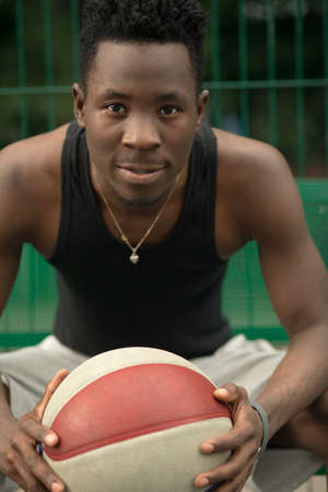 Portrait of african american man sitting on basketball court