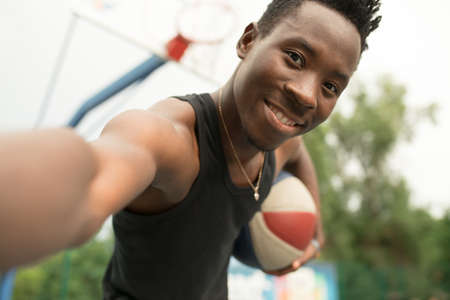 Portrait of african american man on basketball court make selfieの写真素材