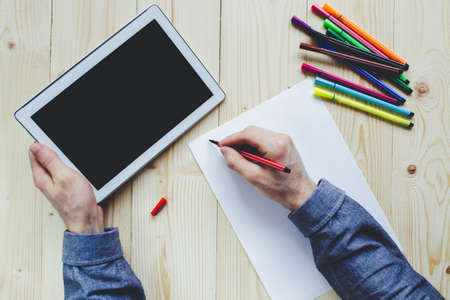 Male hand writing on a felt pen from tablet PC black screenの写真素材