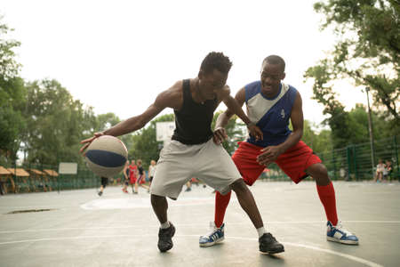 African american man friends playing on basketball court. Real authentic activity.の写真素材