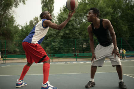 African american man friends playing on basketball court. Real authentic activity.の写真素材