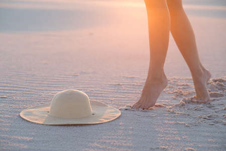 Hat, sand and female legs. Beach holidays concept.の写真素材