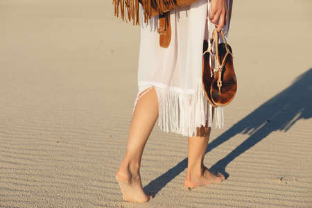 Female legs barefoot goes on a sand in desert or beach