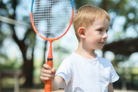 Little boy plays badminton in a pine forest, active rest at a natureの写真素材