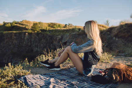 Hiker girl. Trip alone. Young woman travel with adventure. She sitting on nature and looks to quarry.の写真素材
