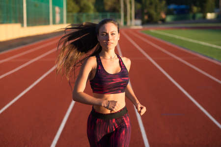 Professional sportswoman athlete sprinter running on stadium track in evening. Healthy lifestyle concept. Forward to the victory.の写真素材
