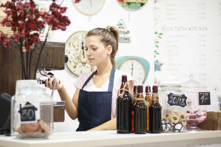 Young woman barista makes coffee in her shop