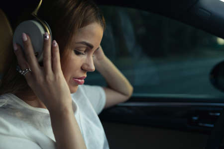 Luxury woman listen music with headphones in her comfortable carの写真素材