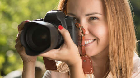 Woman photographer make shoot holding camera near her face