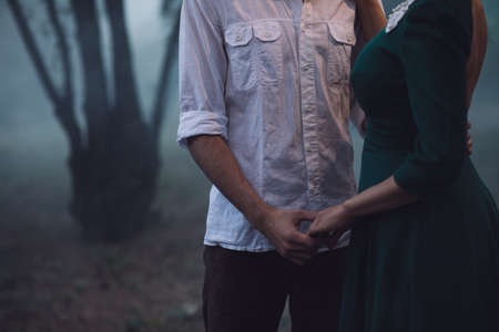 Loving couple in a foggy forest, they hold handsの写真素材