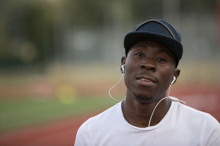Portrait of african american male sportsman listen music in earphones on stadium trackの写真素材