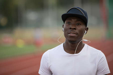Portrait of african american male sportsman listen music in earphones on stadium trackの写真素材