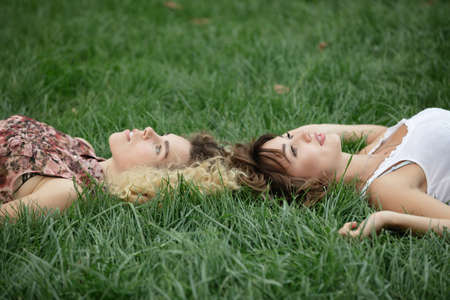 Two women lay and rest on a grassの写真素材