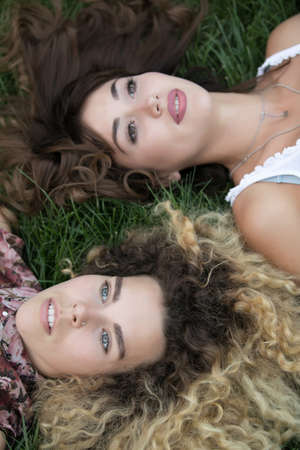 Two women lay and rest on a grassの写真素材