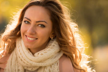 Close up portrait of smiling woman in autumn day at park, blurred background
