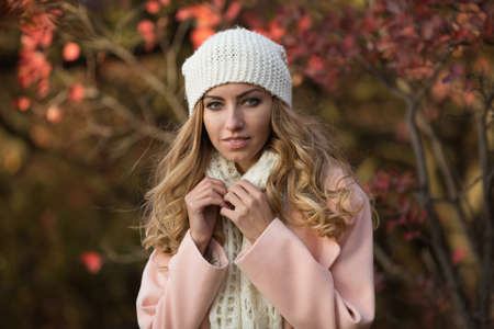 Pretty woman portrait in white hat at the autumn day, she standing in park, colorful foliage aroundの写真素材