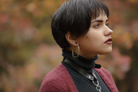 Unconventional woman portrait in marsala color cardigan with black leather sword beltの写真素材