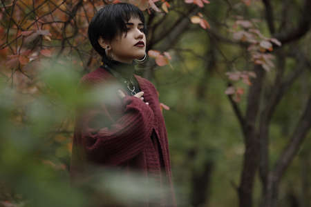 Unconventional woman portrait in marsala color cardigan with black leather sword beltの写真素材