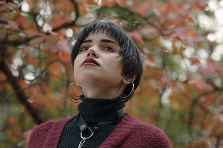 Unconventional woman portrait in marsala color cardigan with black leather sword beltの写真素材