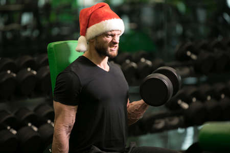 Gym, man in Santa hat pumping bicepの写真素材
