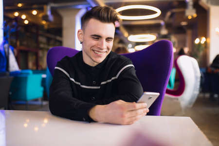 Young man using smartphone sitting in a futuristic cafe