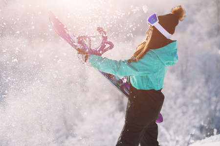 Leisure, sport concept. Snowboarder holding her board and sparks of snow.の写真素材